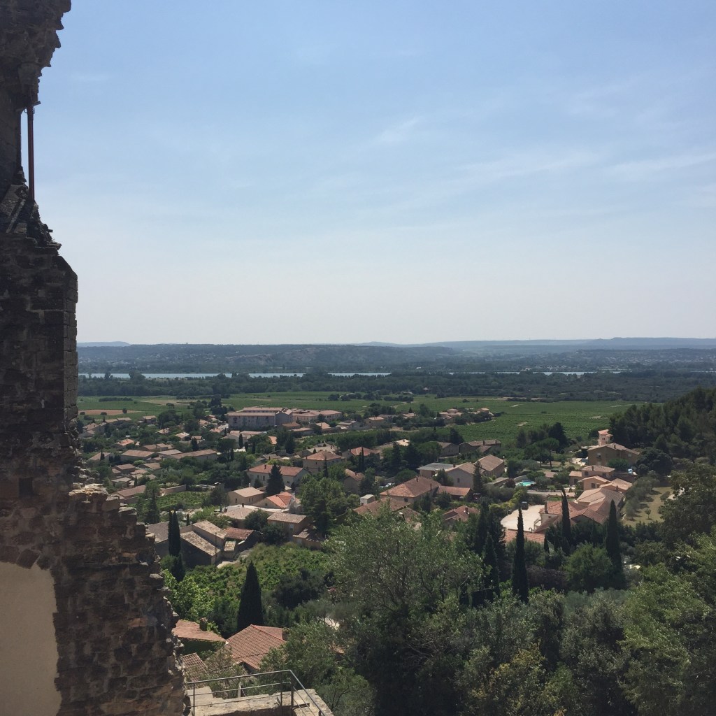 A view through a gap in a ruined stone tower over the rooftops of Châteauneuf-du-Pape to the Rhône valley beyond.