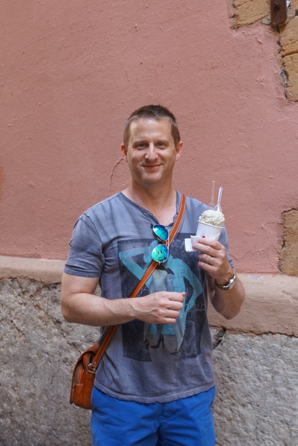 Chris standing against a pink rendered wall holding an ice cream.