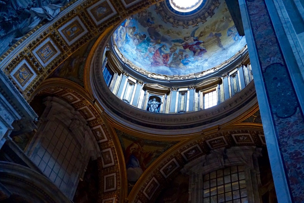 The dome and drum of St Peter's seen from an angle, with the coffered vault and frescoed pendentives below