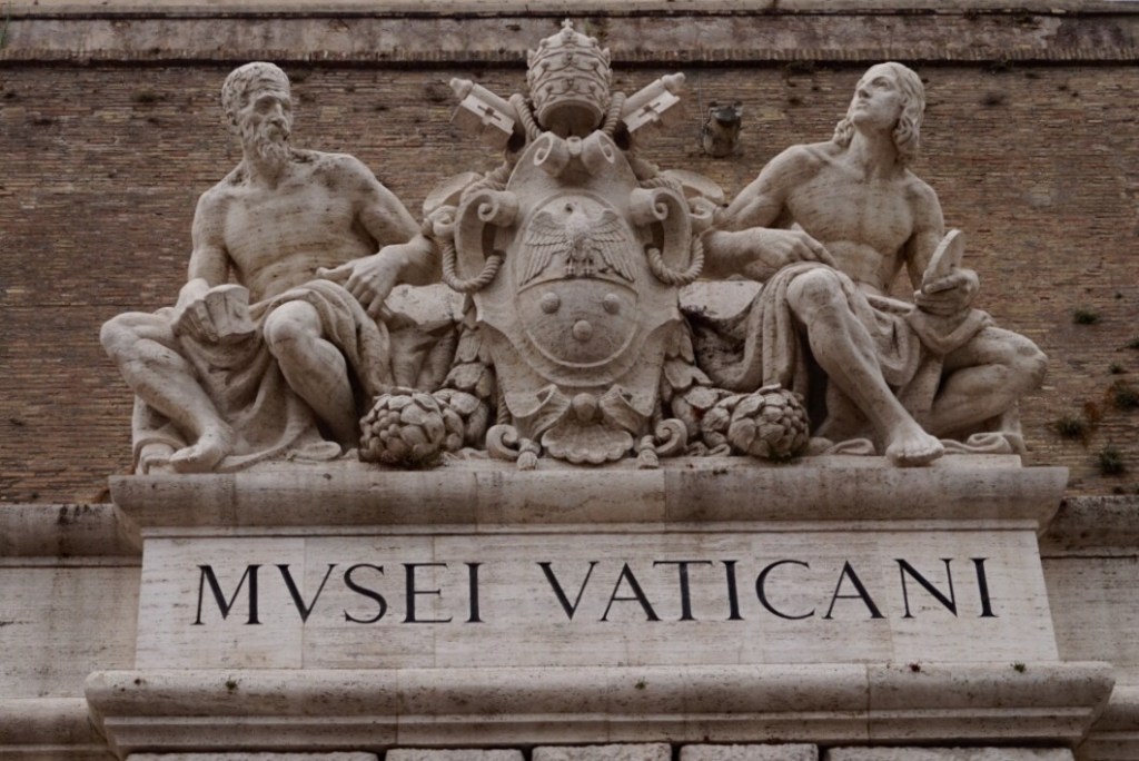 The entrance to the Vatican Museums, MVSEI VATICANI carved in travertine beneath two seated sculpted figures