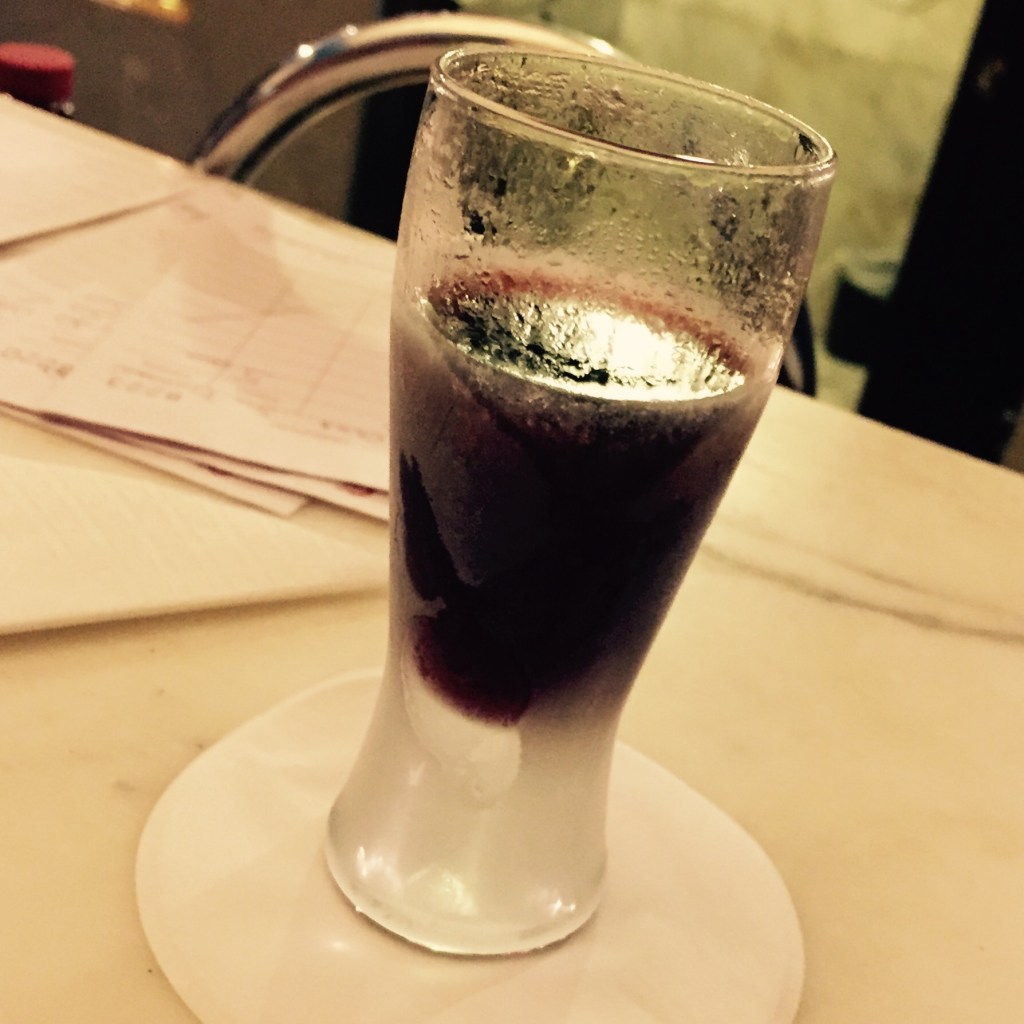 A glass of red wine held up above a restaurant table