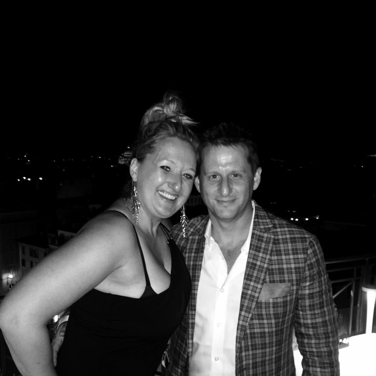Chris and Jen dressed for dinner on the roof terrace at night, the lights of Rome behind them
