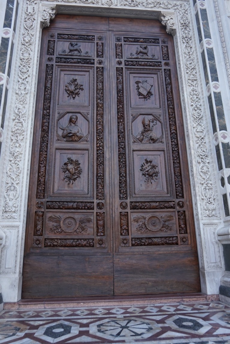 The carved bronze doors of the Duomo in their marble surround