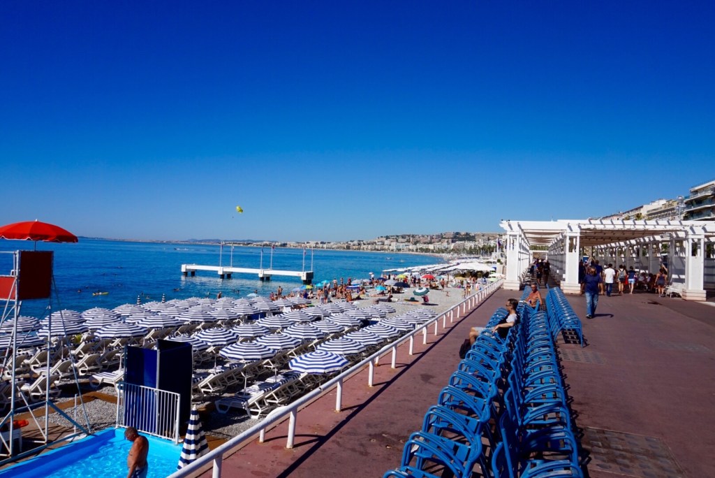 The Nice seafront from the Promenade, ranks of blue loungers and parasols down the beach
