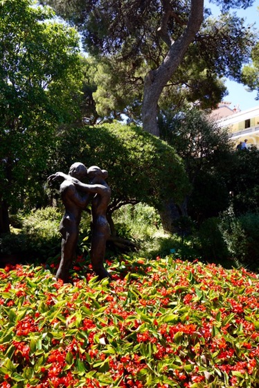 A bronze sculpture of two embracing figures in the palace gardens, standing above a bed of red flowers