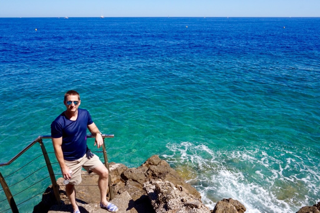 Chris on a flight of steps down to the rocks, turquoise water breaking below