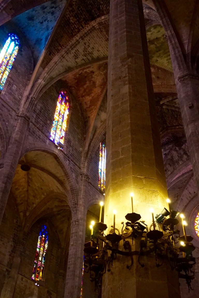 Looking up the vast columns of Palma Cathedral to the stained glass, a wrought-iron candelabra hanging below