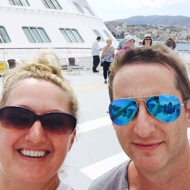 Chris and Jen on the ship's helipad at sail away, other guests and the Mallorcan hills behind