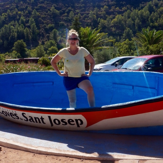Chris standing in an oversized painted boat lettered Coves Sant Josep at the entrance to the caves