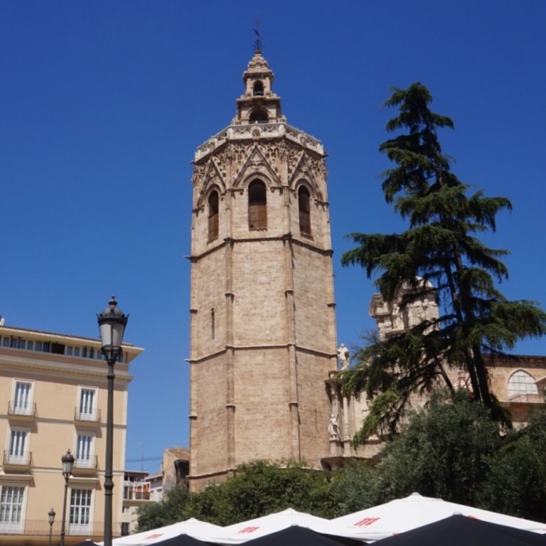 The Micalet bell tower above the Placa de la Reina, market awnings and a crowd below