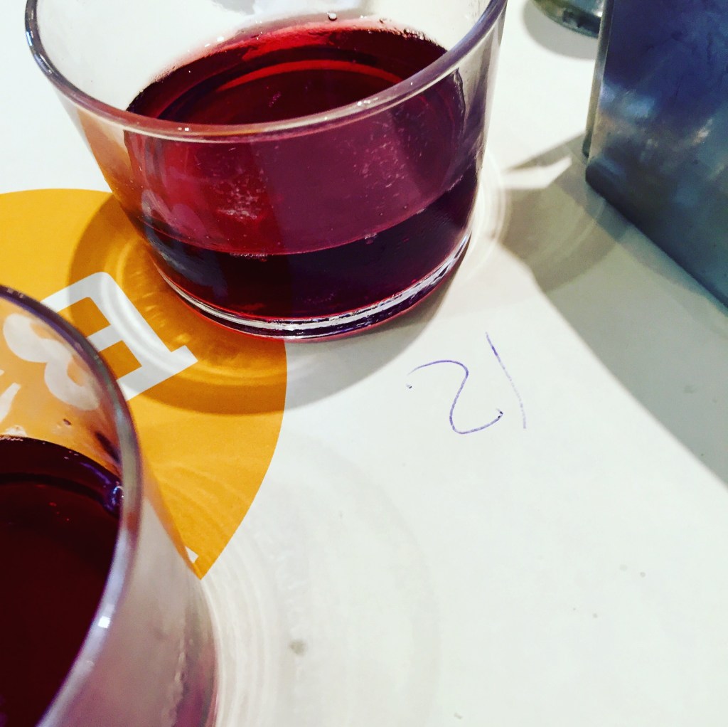A glass of sangria on a table beside the counted skewers