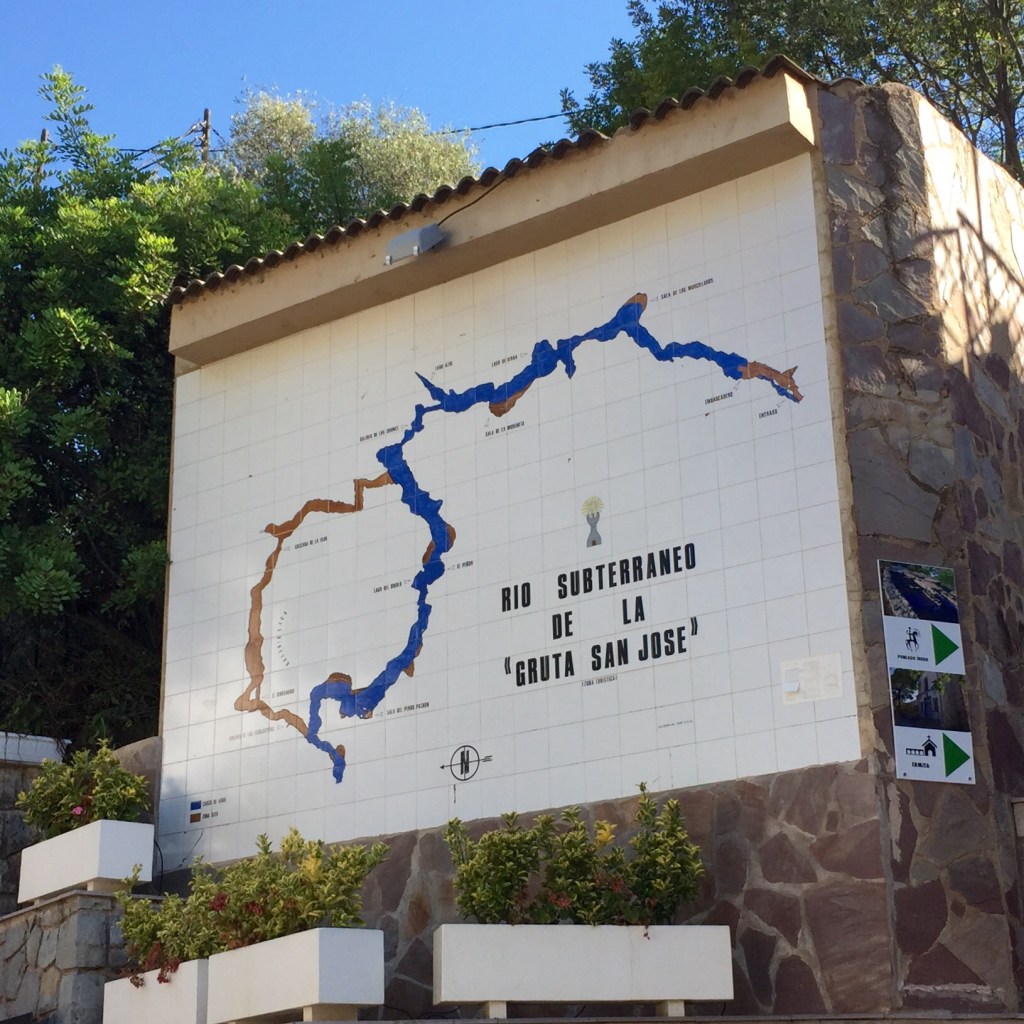 A tiled wall map of the underground river beside the steps up to the cave entrance