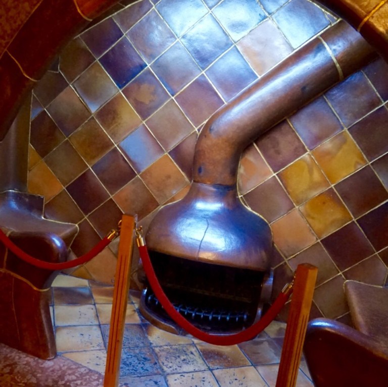 Inside Casa Batllo, the blue-tiled light well and a curved wooden bench
