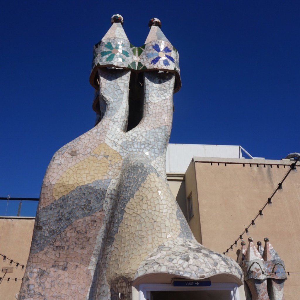 The mosaic-tiled chimney stacks on the roof of Casa Batllo against a blue sky
