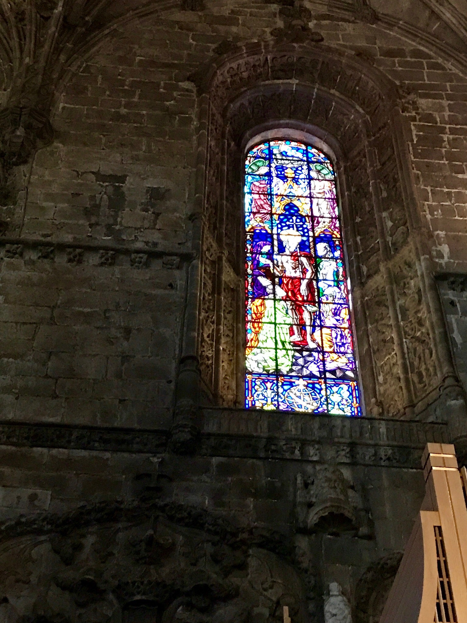 A stained-glass window set deep in the stone wall of the monastery church
