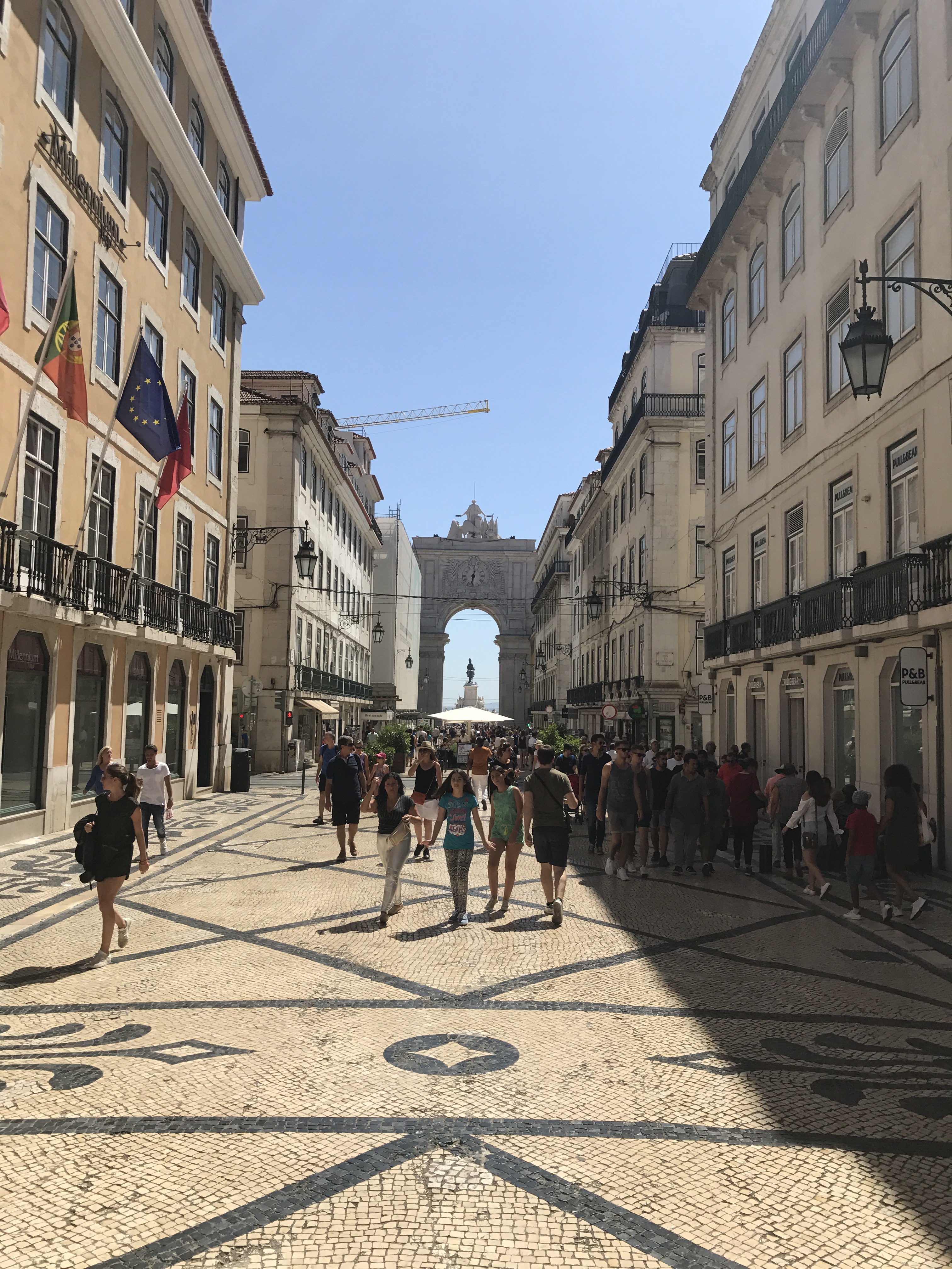 A pedestrian street in Lisbon, its patterned calçada paving running away between the buildings