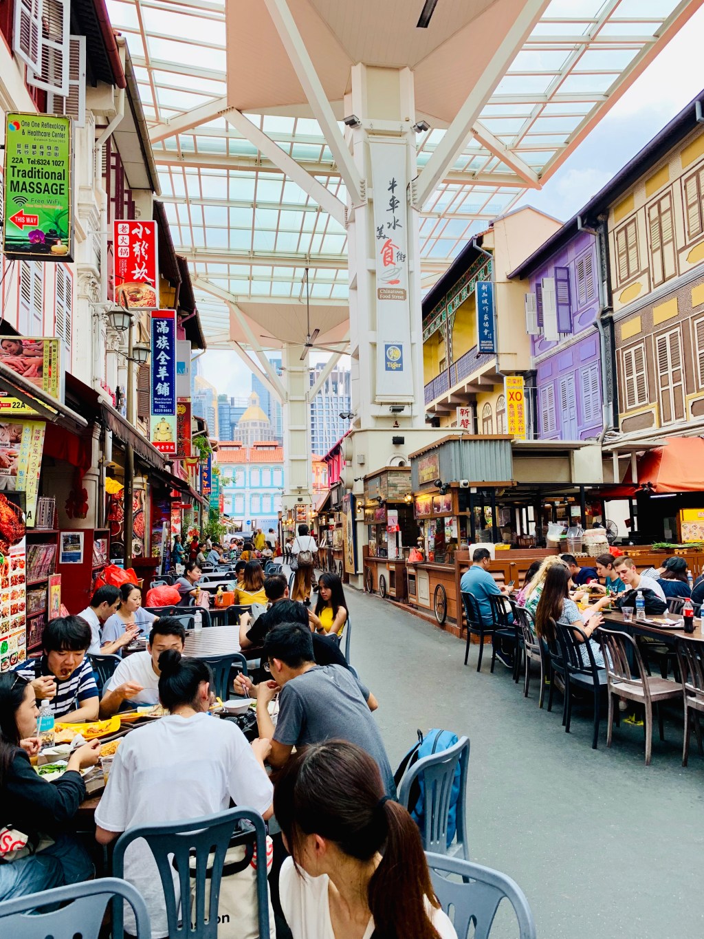 A covered food street in Chinatown, tables and diners running away under the awning