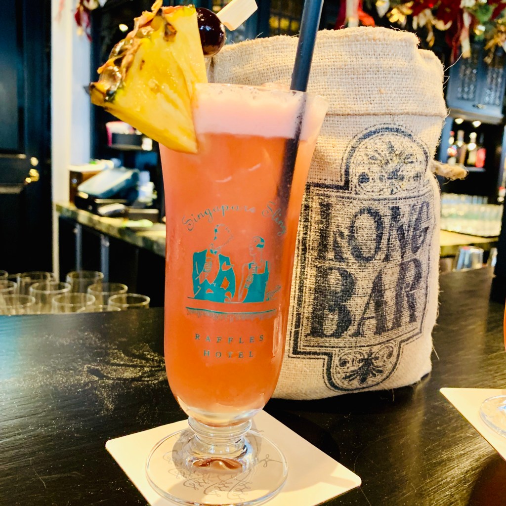 A Singapore Sling at the Long Bar, the mug beside it stamped LONG BAR