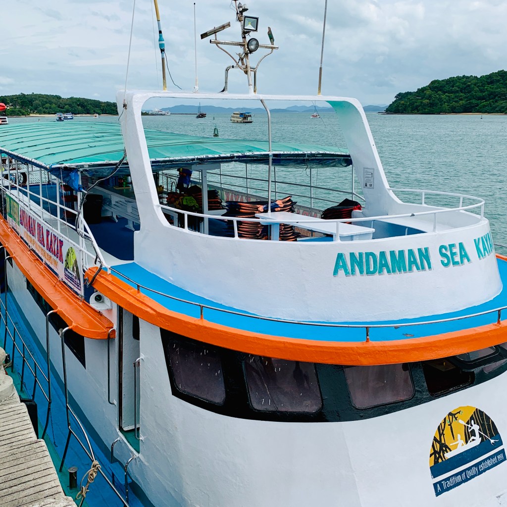 The blue and orange tender alongside, ANDAMAN SEA painted on her bow
