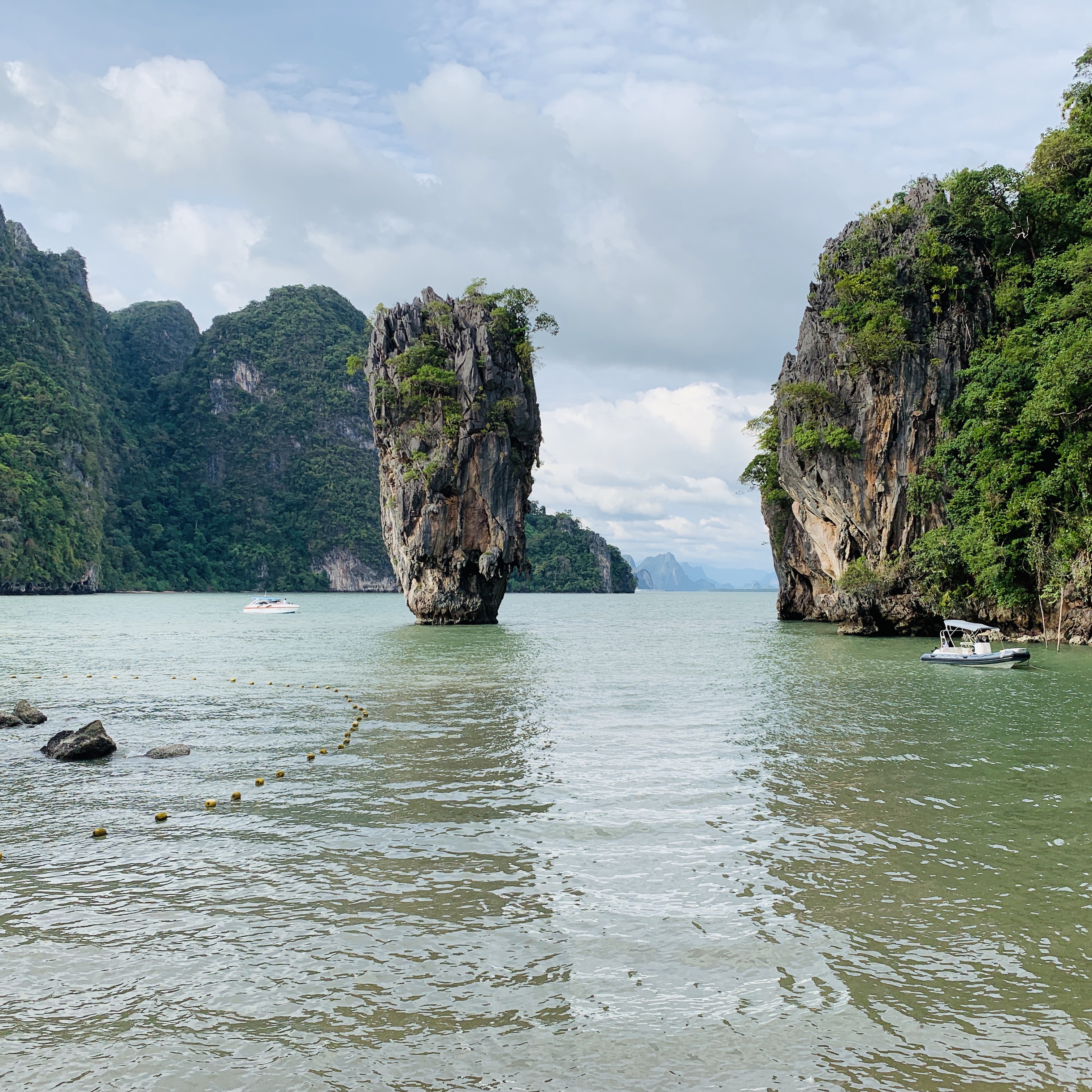 The limestone stack of Ko Tapu standing out of the water in Phang Nga Bay, a longtail boat passing