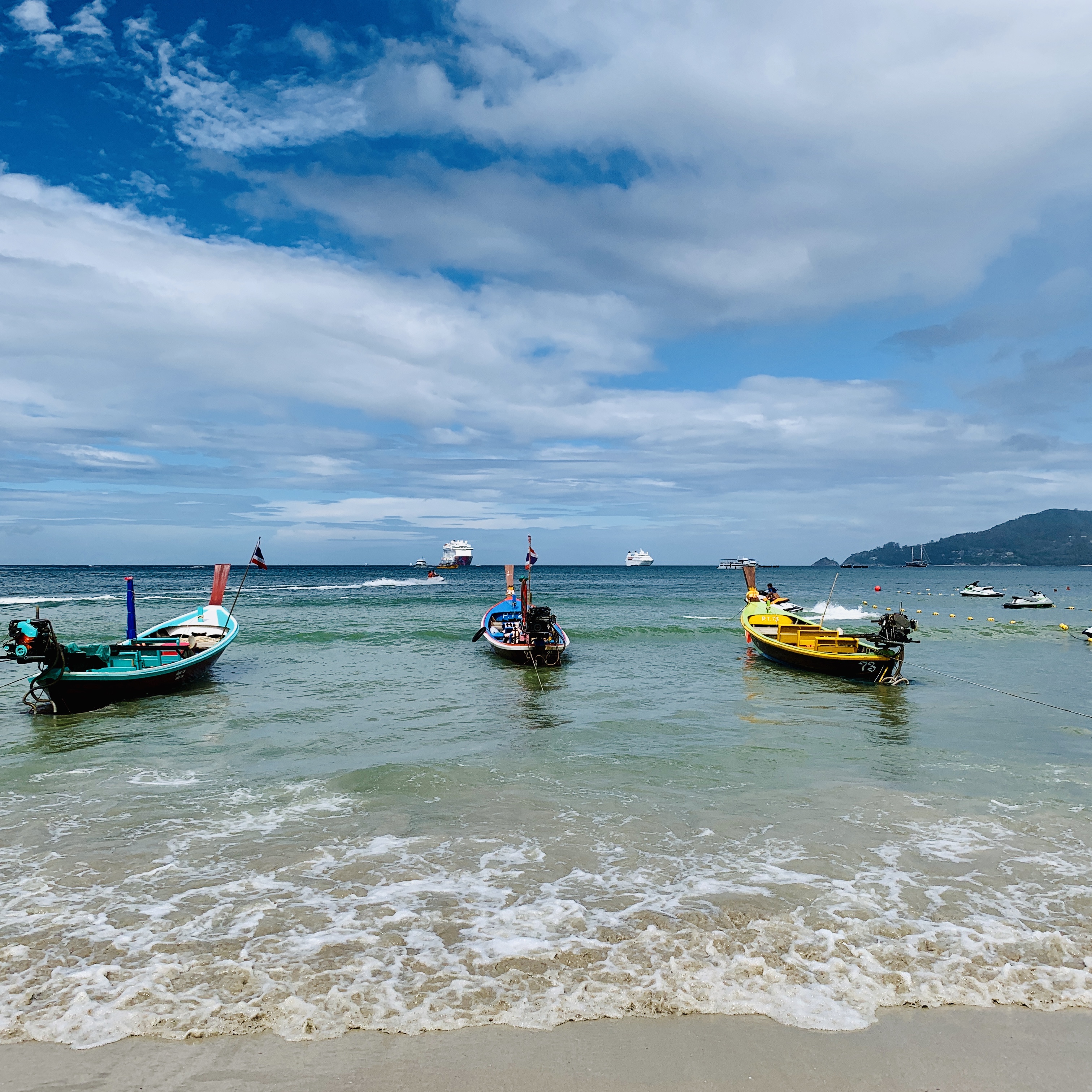 Longtail boats drawn up off the beach, the ship anchored out beyond them