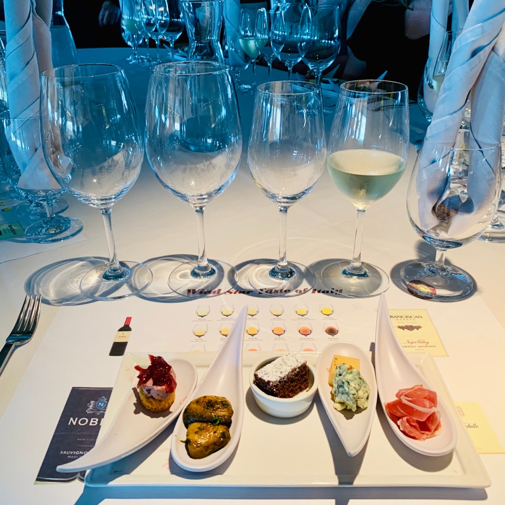 A tasting laid out on white linen, wine glasses and small plates in a row