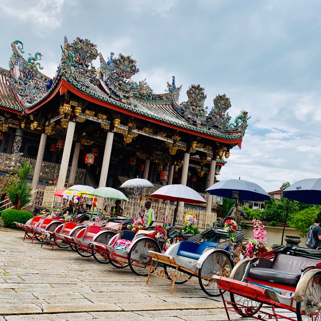 The clan temple in Penang, trishaws with fringed umbrellas drawn up in front of it