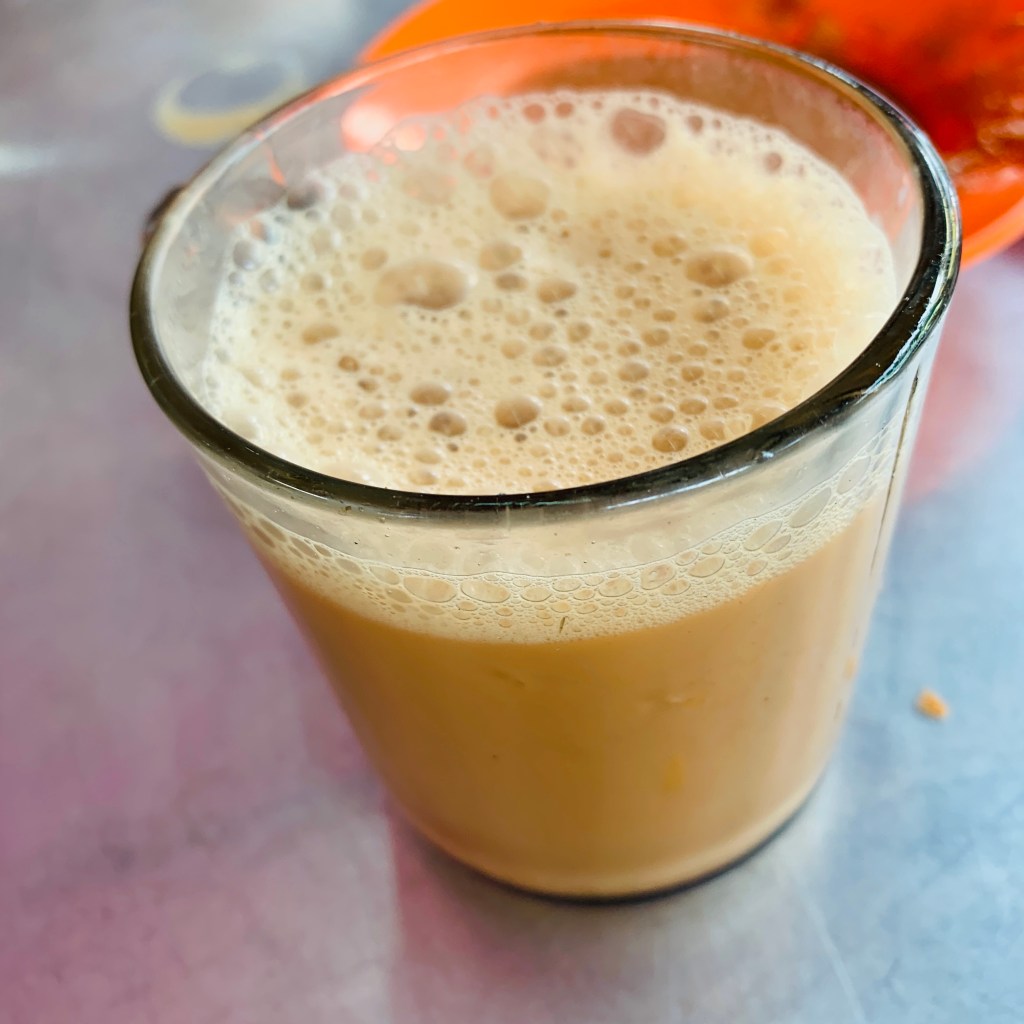 A tall glass of freshly pressed juice, still frothing at the top