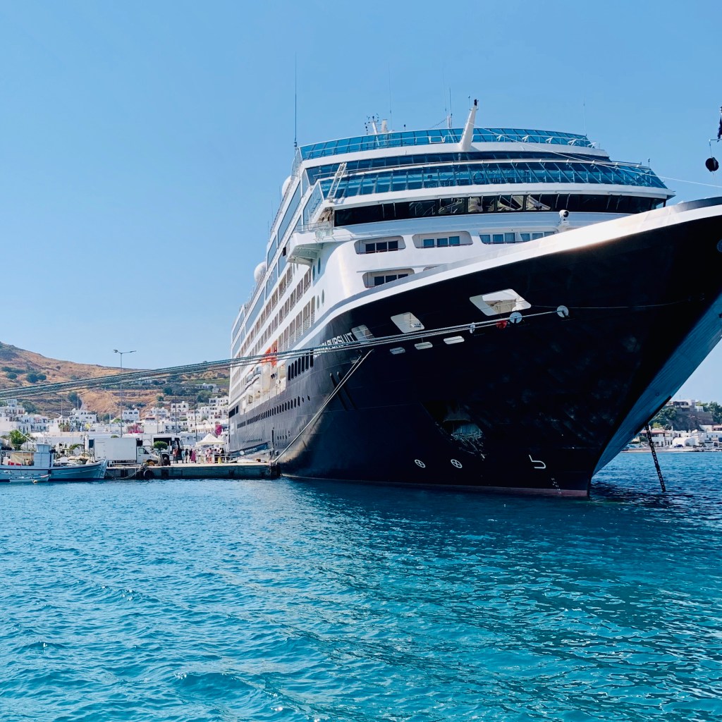 The Azamara Pursuit lying in the bay at Skala, the white town climbing the hillside behind her.