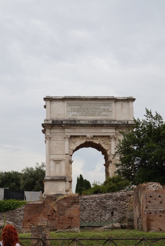 The Arch of Titus standing above the Forum, its inscription running across the attic