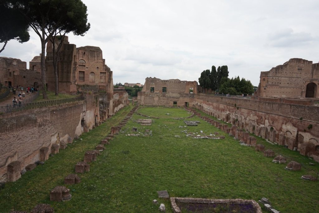 The sunken green oval of the Stadium of Domitian on the Palatine, brick walls on all four sides