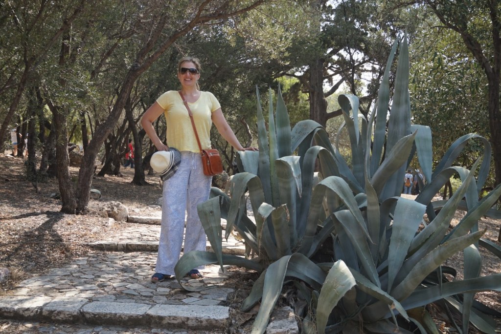 Jen beside an enormous agave on the flagstone path up to the Acropolis, olives and pines overhead