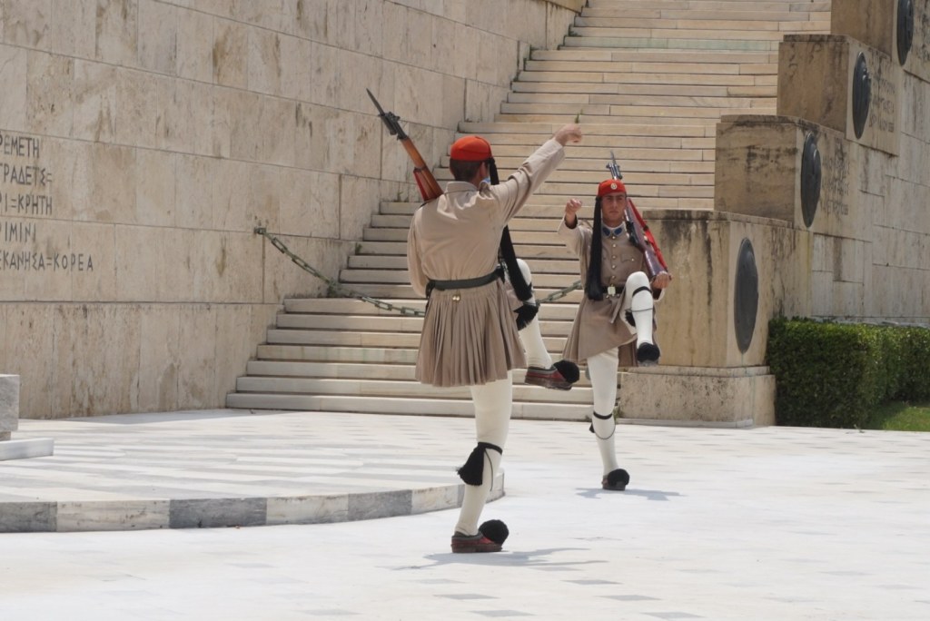 Two Evzones mid high-kick on the steps below the Tomb of the Unknown Soldier
