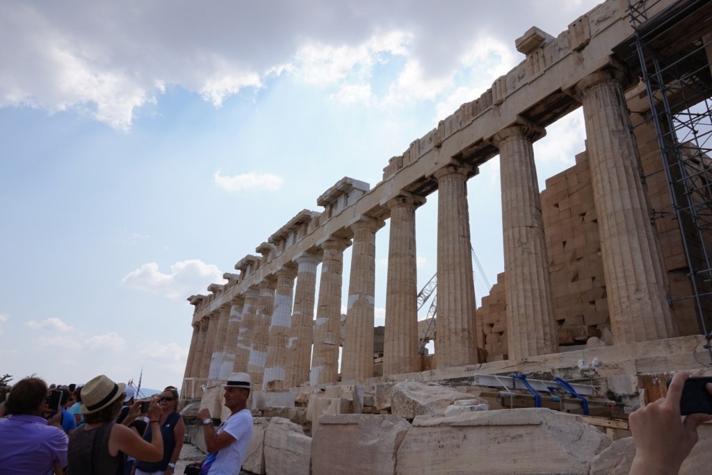 The long north colonnade of the Parthenon against a blue and white sky, restoration scaffolding at one end