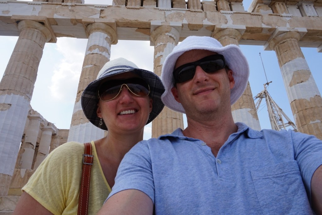 Chris and Jen in white sun hats in front of the Parthenon columns