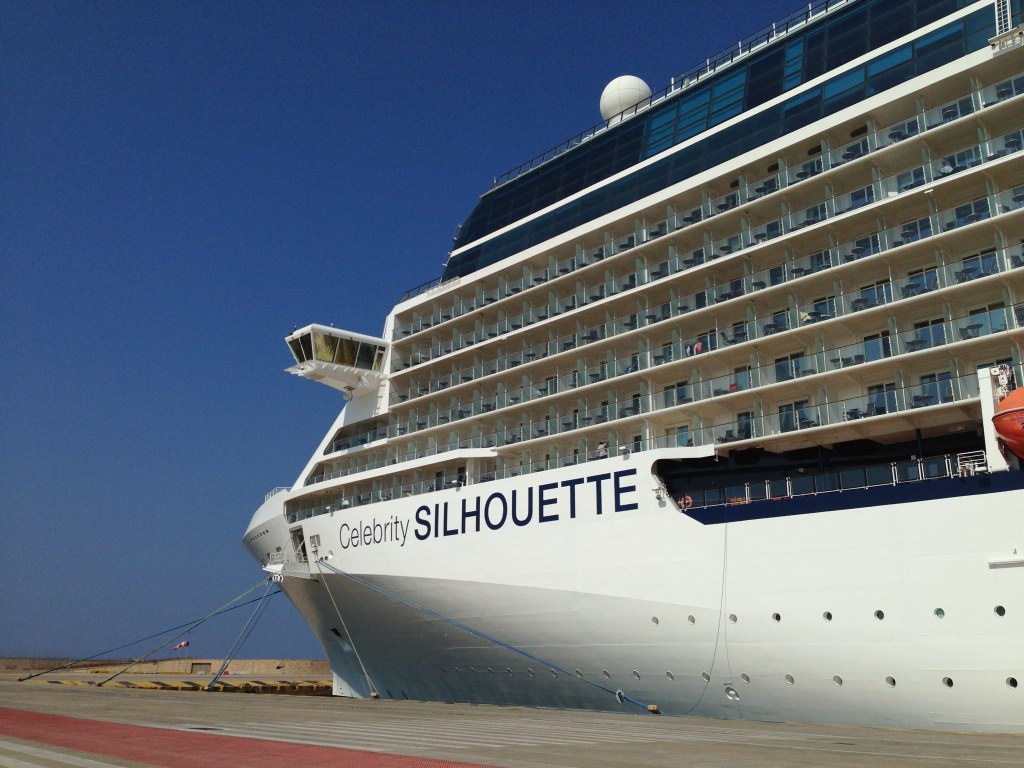 The bow of Celebrity Silhouette towering over the quay at Piraeus, the ship's name in black on the white hull