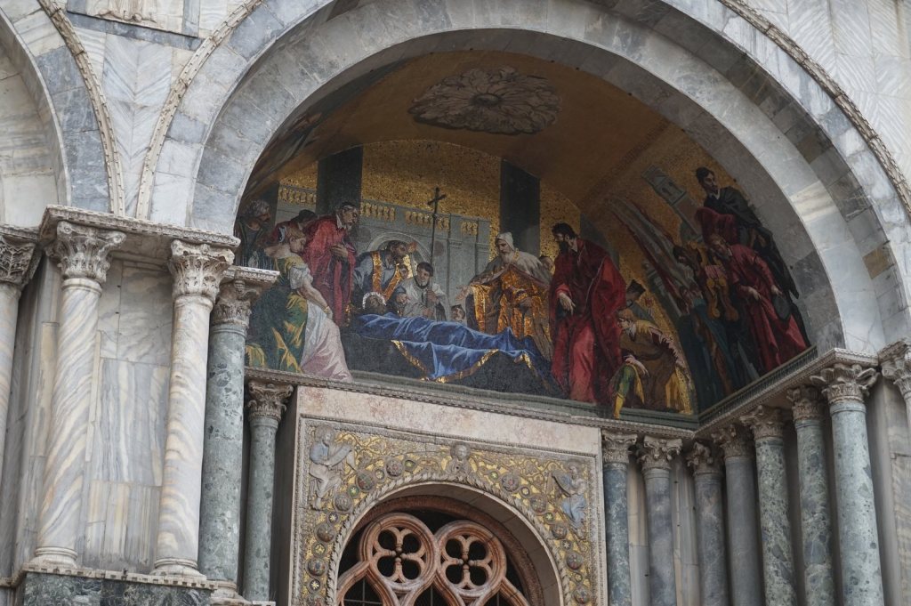 A gold mosaic lunette above a side doorway of St Mark's, figures carrying a shrouded body