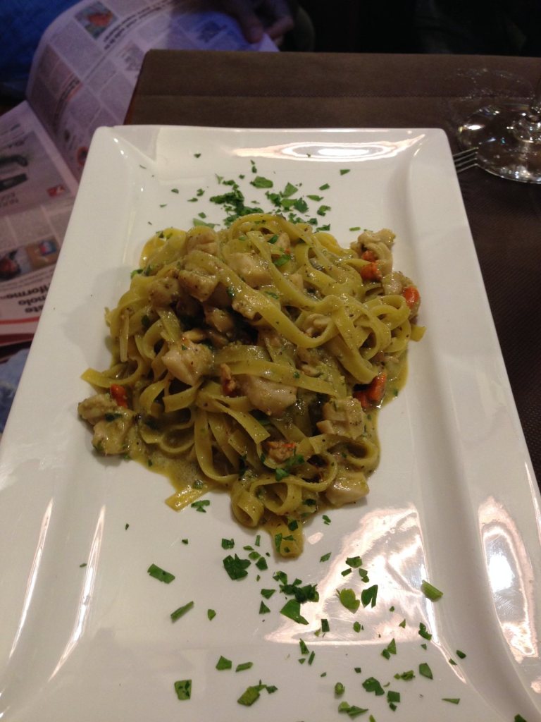 A plate of green herbed ribbon pasta scattered with chopped parsley