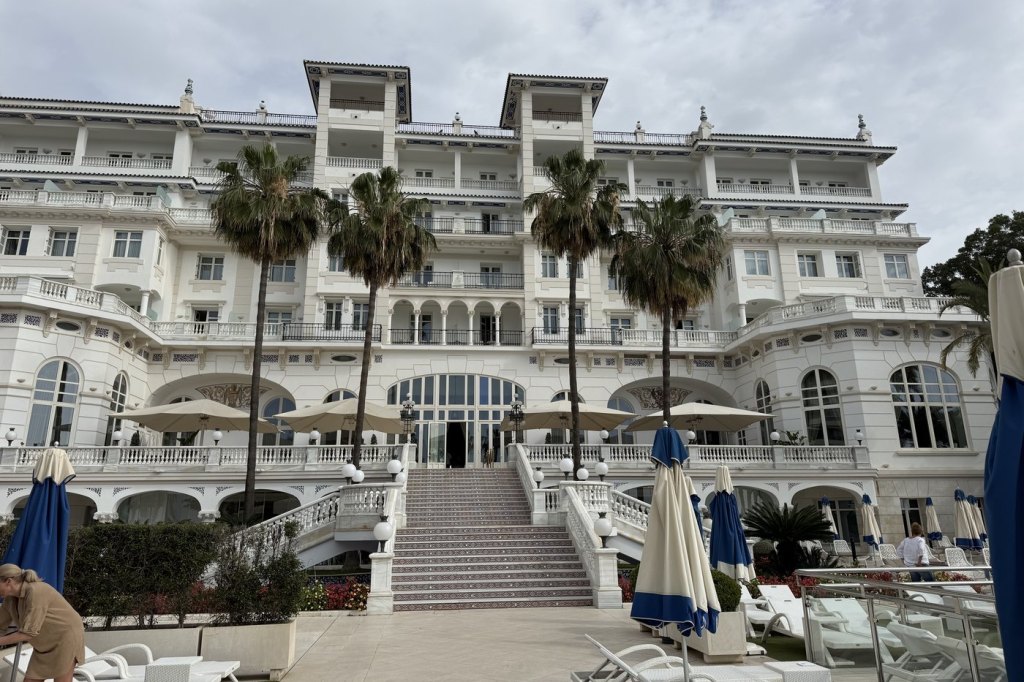 The white Belle Époque facade of the Gran Hotel Miramar in Málaga, with palm trees and a pool terrace in front.