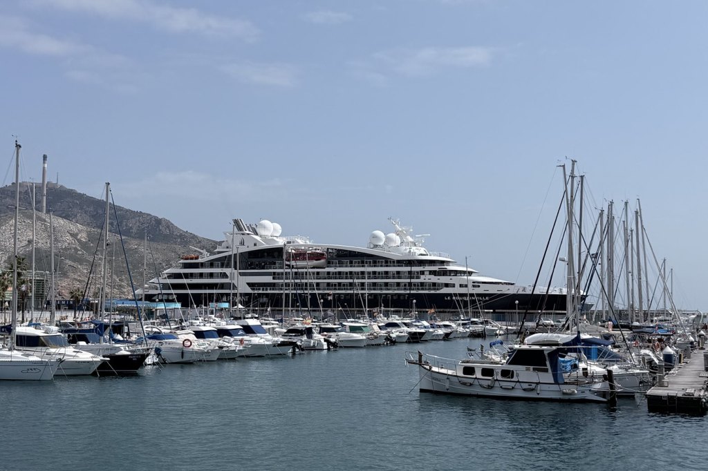 The PONANT ship Le Bougainville docked beyond a marina full of sailboats and yachts in Cartagena, Spain.