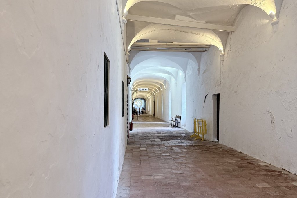 A long whitewashed barrel-vaulted corridor in the Royal Carthusian Monastery at Valldemossa, receding toward the light.